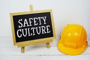 Safety Culture text on blackboard with safety helmet on wooden background