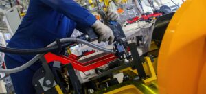 Workers engage in detailed assembly tasks within a high-tech factory, showcasing advanced machinery and collaborative efforts.